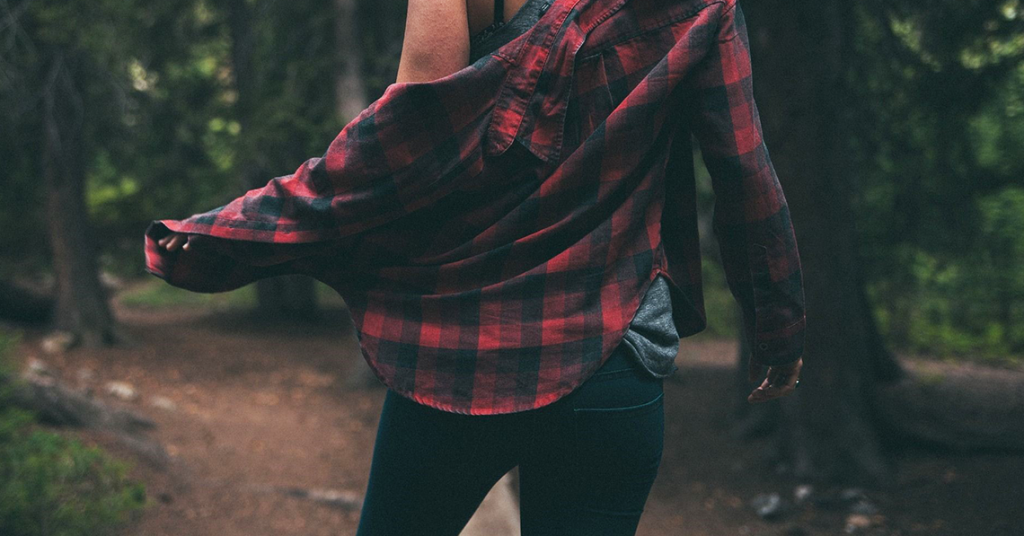 femeie care poartă o cămașă în carouri în pădure